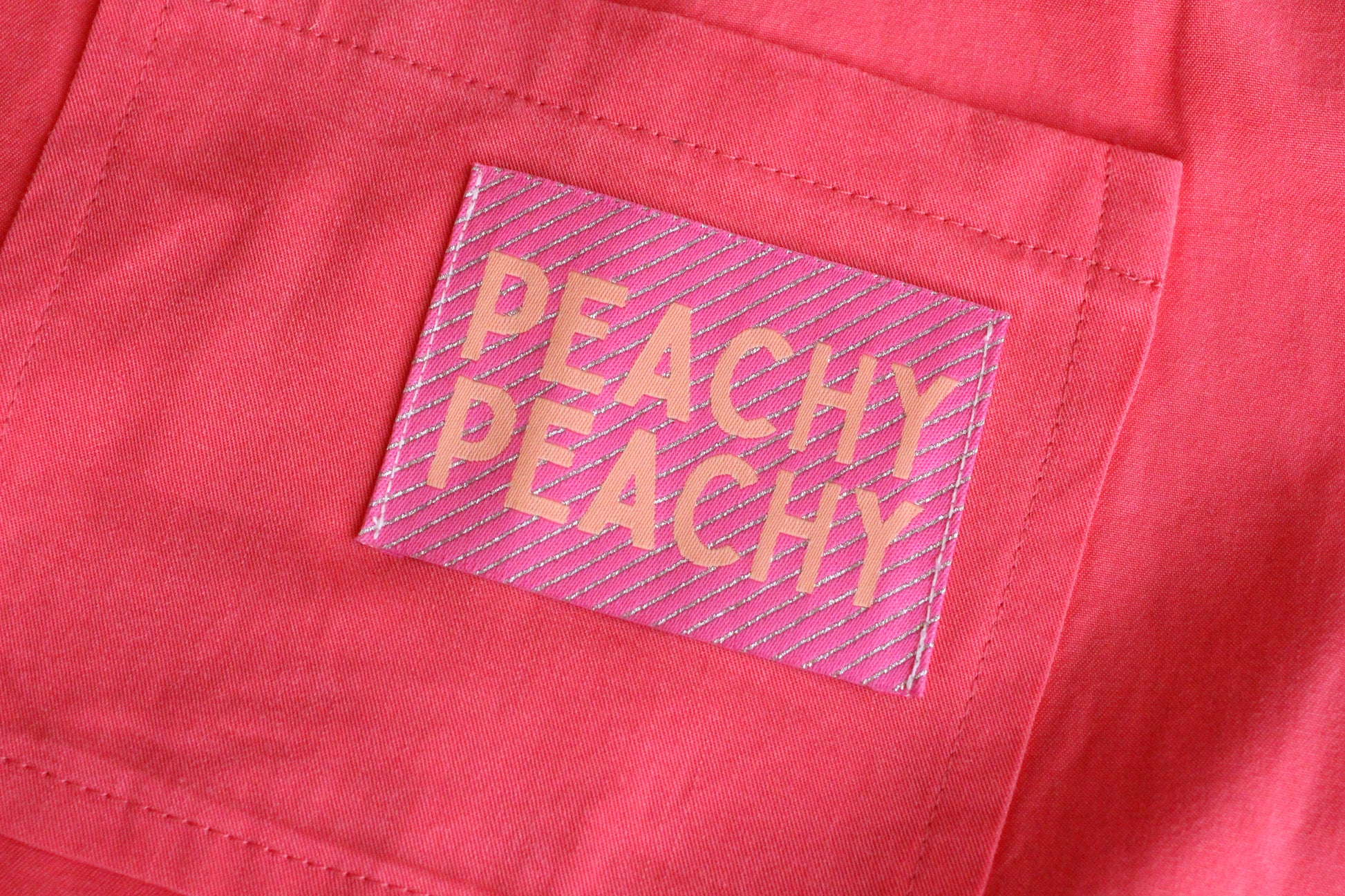 Large peach-colored woven sewing labels from The Cosy Club Handmade, featuring the Peachy Peach design for clothing and crafts.