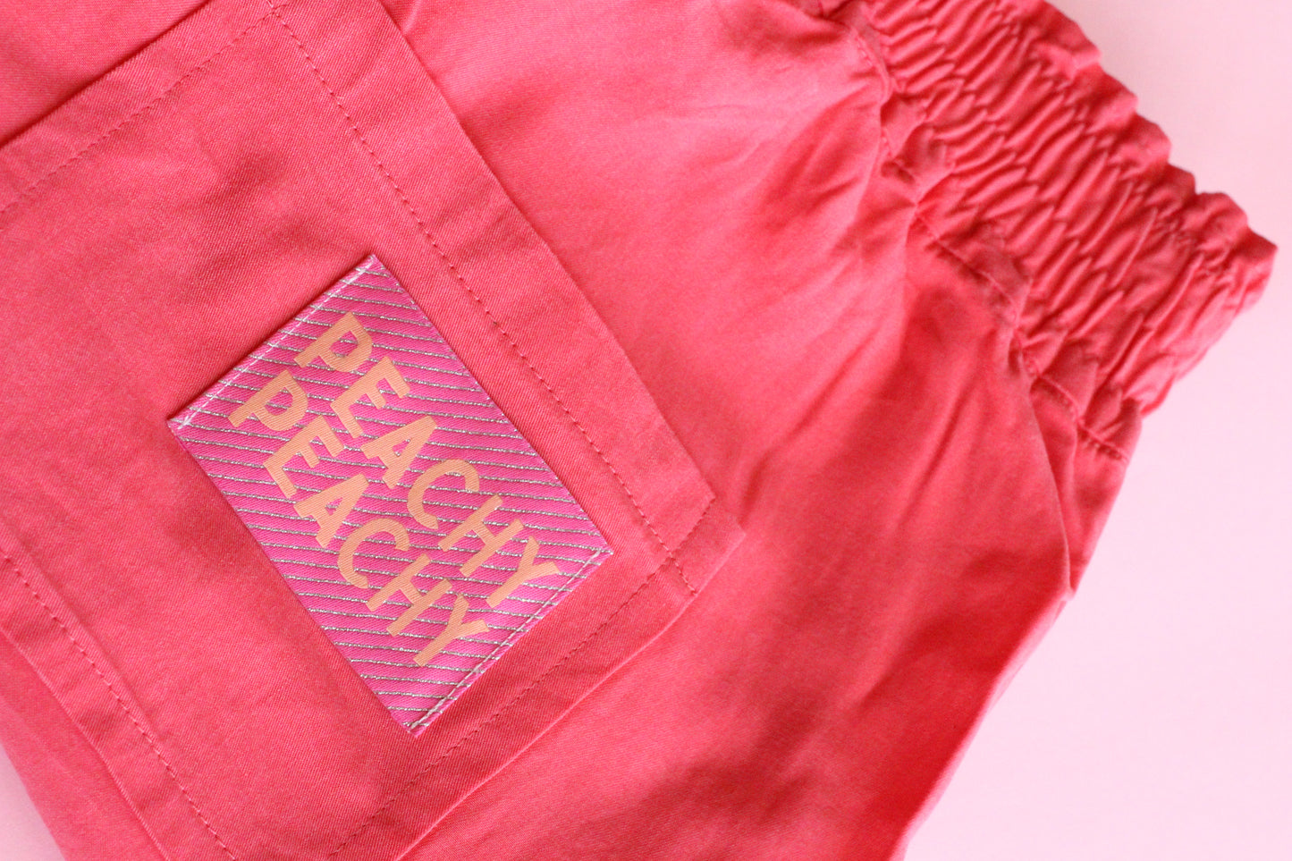 Large peach-colored woven sewing labels by The Cosy Club Handmade, featuring "Peachy Peach" text on fabric tags.