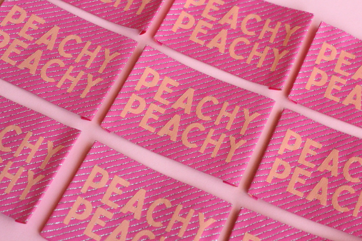 Large peach-colored woven sewing labels from The Cosy Club Handmade, featuring the Peachy Peach design on fabric.