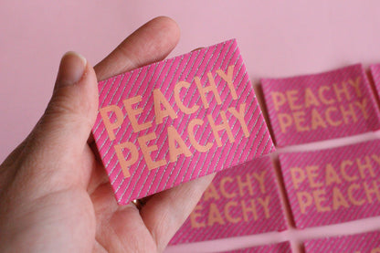 Large peach-colored woven sewing labels featuring "Peachy Peach" text from The Cosy Club Handmade, designed for fabric and craft projects.