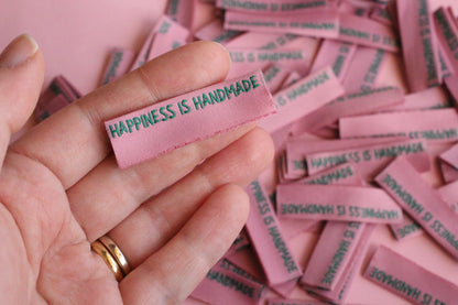 Six side seam handmade sewing labels from The Cosy Club Handmade with "Happiness is Handmade" text for personalized clothing.