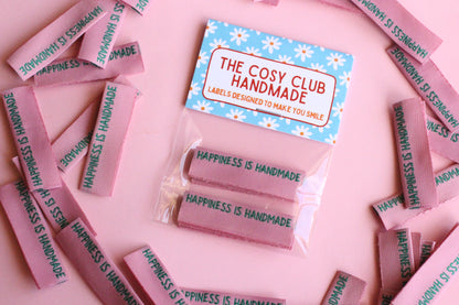 Six handmade side seam sewing labels from The Cosy Club Handmade with positive "Happiness is Handmade" text for clothing tags.