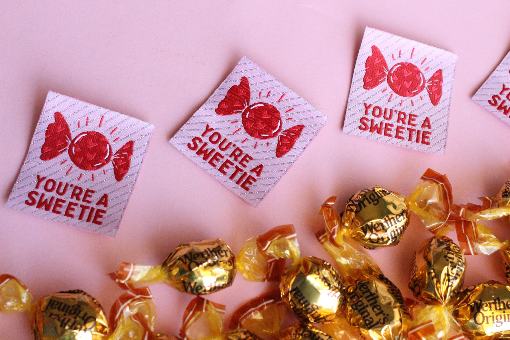 Handmade "You're a SWEETIE" candy-themed sewing labels by The Cosy Club Handmade, featuring colorful labels on fabric.