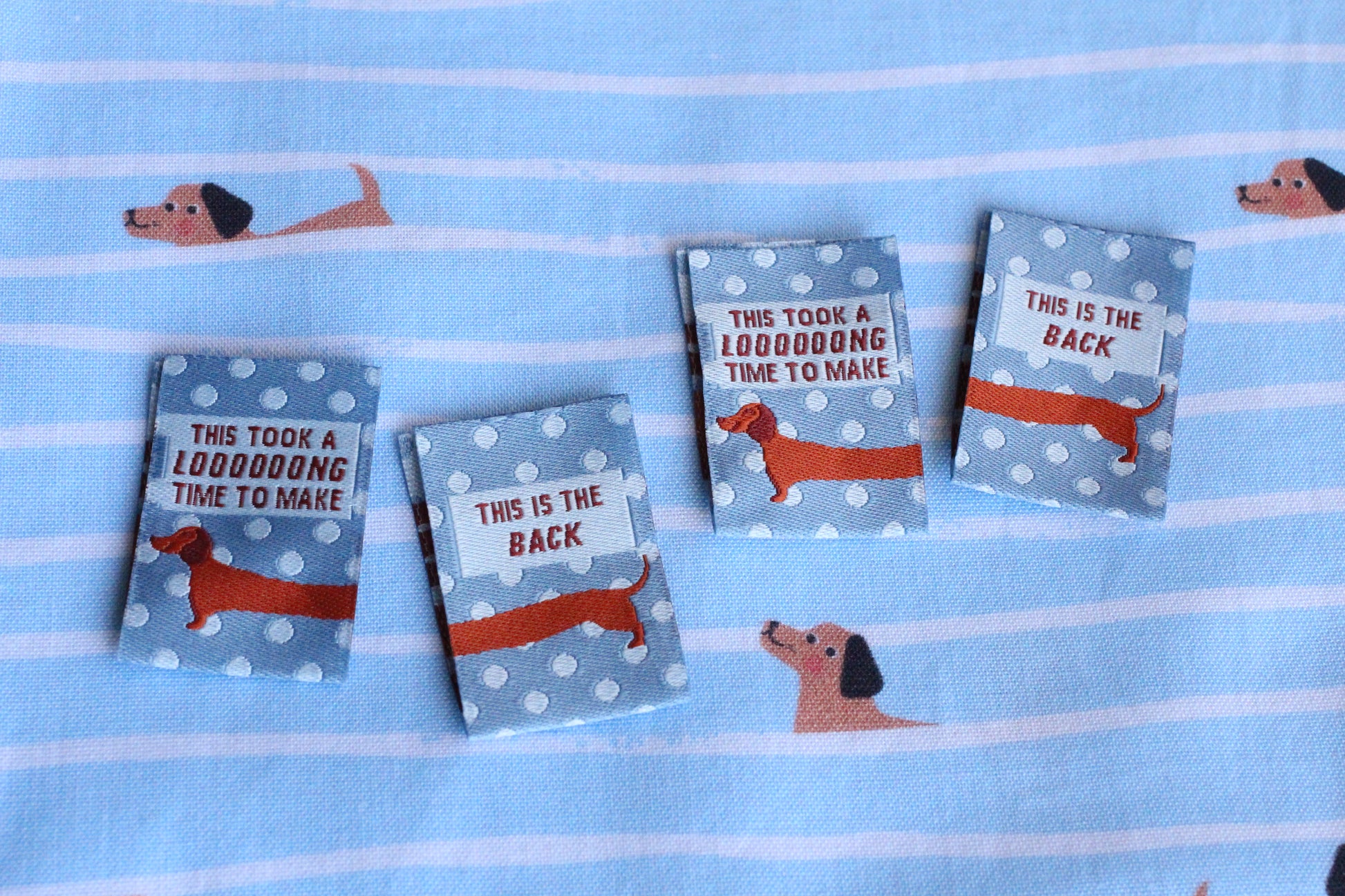 Blue sausage dog sewing labels by The Cosy Club Handmade, double-sided, perfect for crafting or sewing projects.