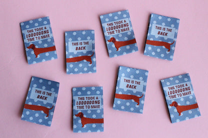Blue Sausage Dog sewing labels from The Cosy Club Handmade, double-sided fabric tags with adorable dog design, perfect for handmade projects.
