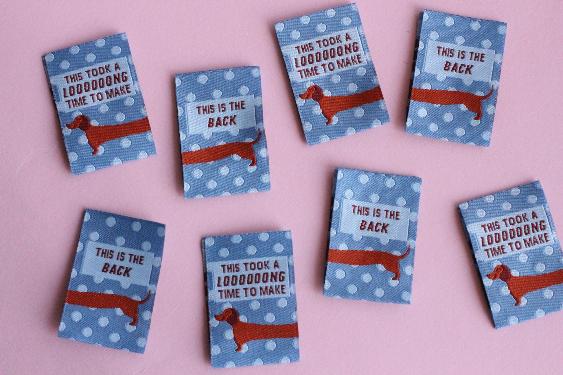 Blue sausage dog sewing labels by The Cosy Club Handmade, double-sided fabric tags with playful dog design for sewing projects.