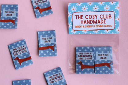 Blue sausage dog sewing labels from The Cosy Club Handmade, double-sided fabric tags featuring adorable dog design for crafting and sewing projects.