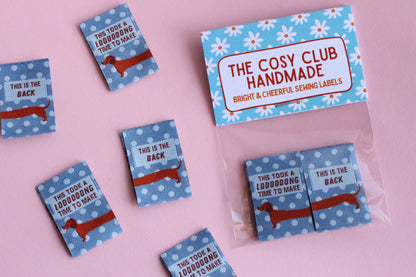 Blue sausage dog sewing labels from The Cosy Club Handmade, double-sided fabric tags with cute dog design for crafting projects.