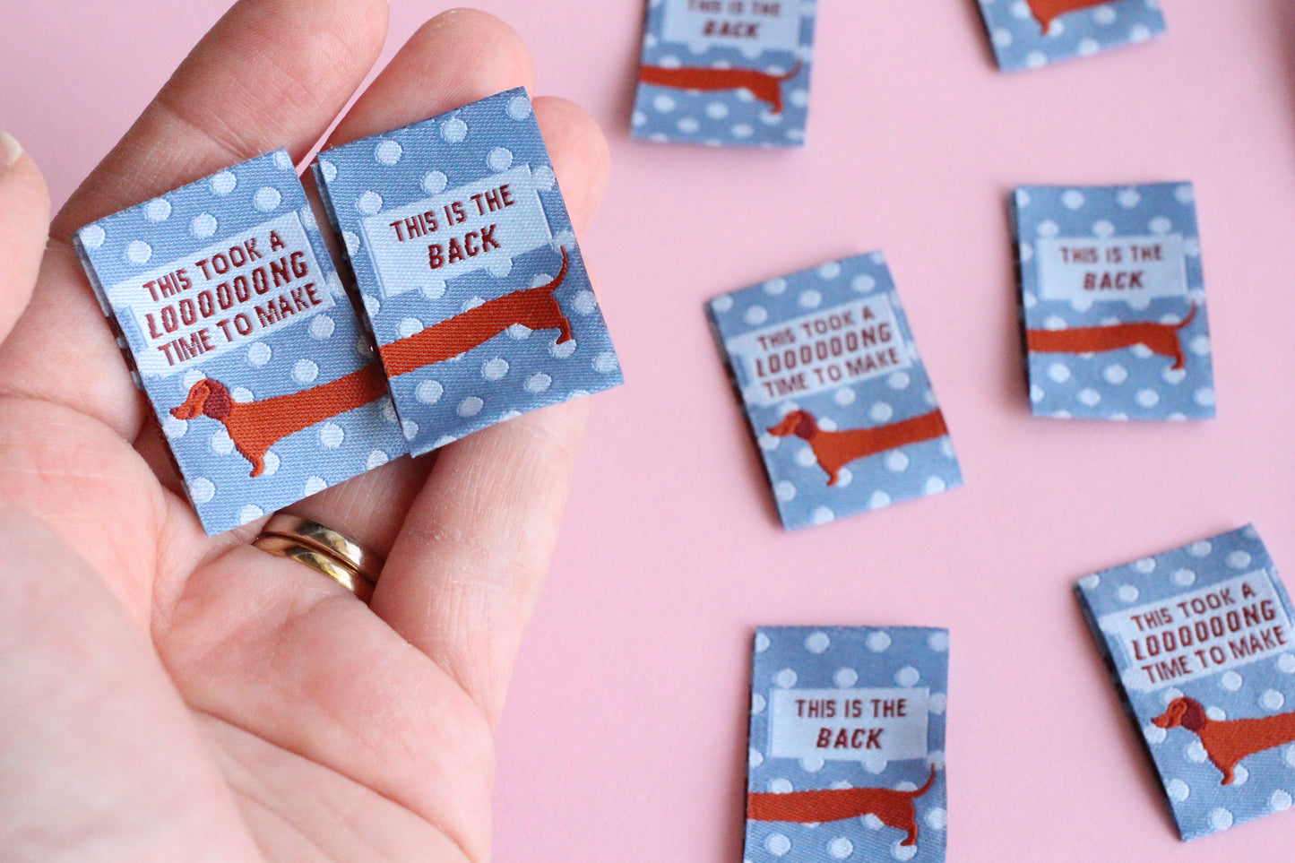 Blue sausage dog sewing labels from The Cosy Club Handmade, double-sided fabric tags with adorable dog design.