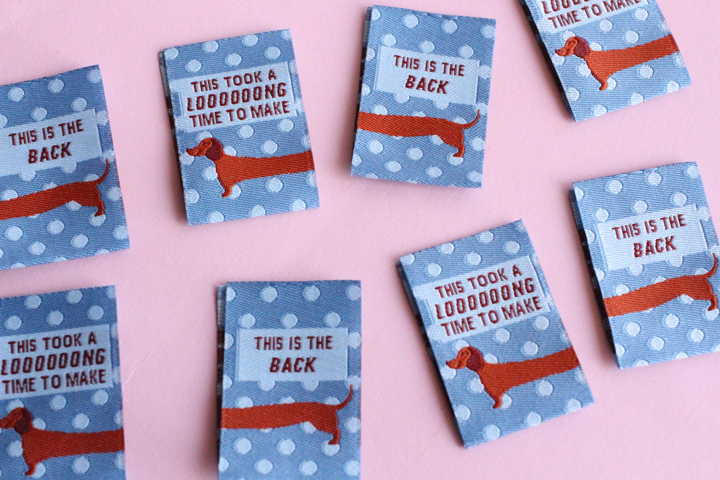 Set of 6 double-sided sewing labels featuring blue sausage dog design from The Cosy Club Handmade, perfect for clothing or craft projects.