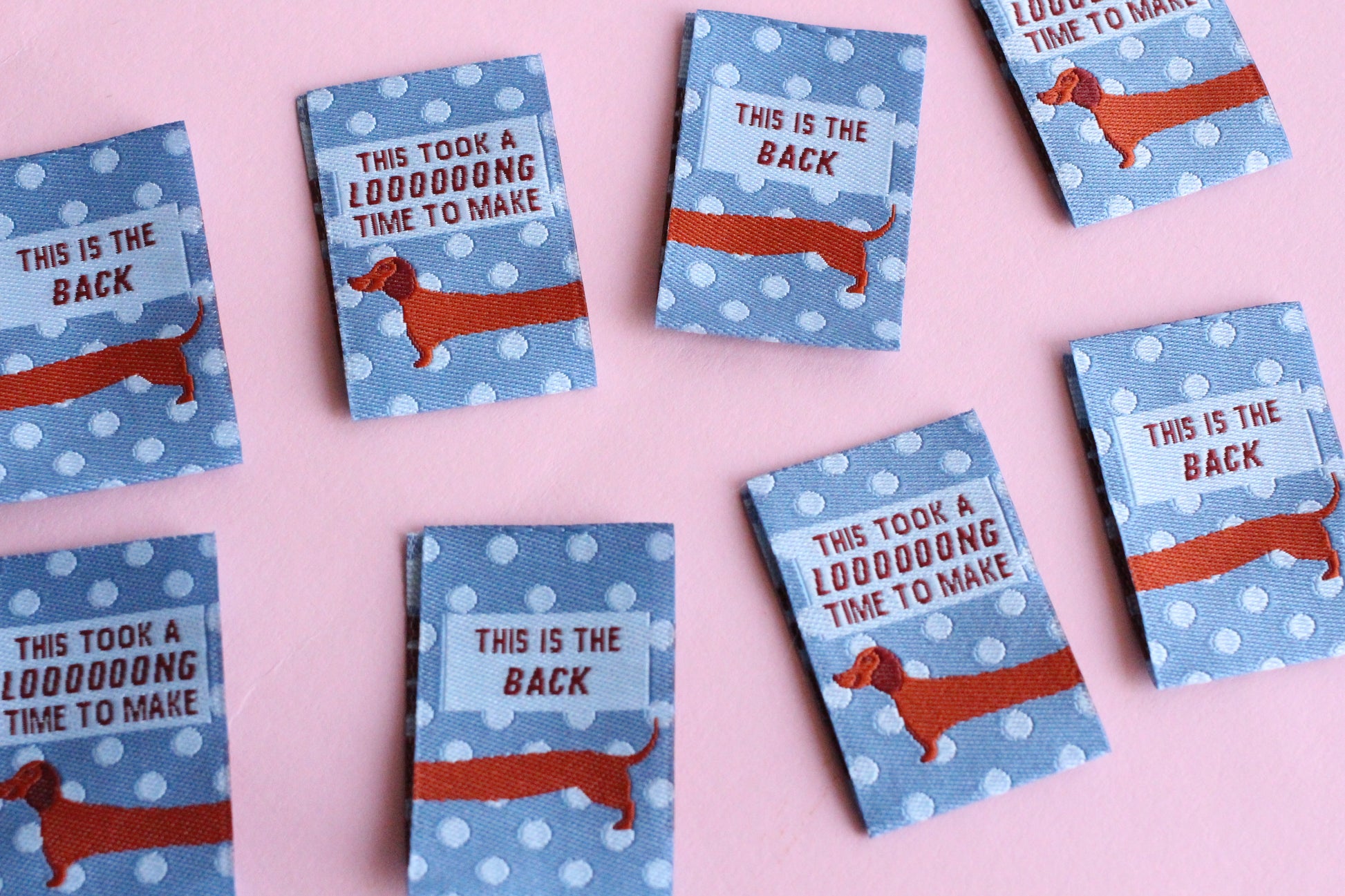 Set of 6 double-sided sewing labels featuring blue sausage dog design from The Cosy Club Handmade, perfect for clothing or craft projects.