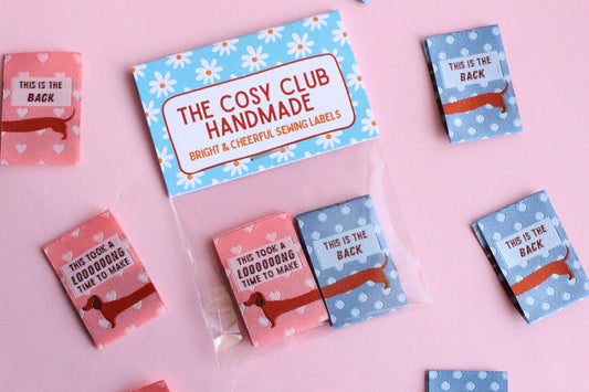 Pink and blue sausage dog sewing labels by The Cosy Club Handmade, double-sided fabric tags for sewing projects.