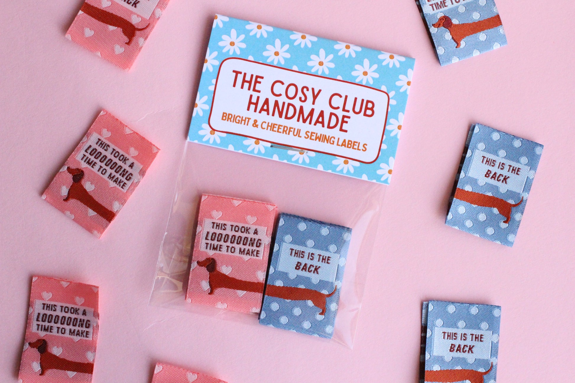 Pink and blue sausage dog sewing labels from The Cosy Club Handmade, double-sided fabric tags for crafts and sewing projects.