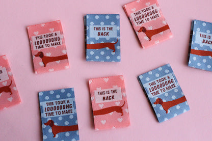 Pink and blue sausage dog sewing labels from The Cosy Club Handmade, double-sided fabric labels for sewing and crafts.