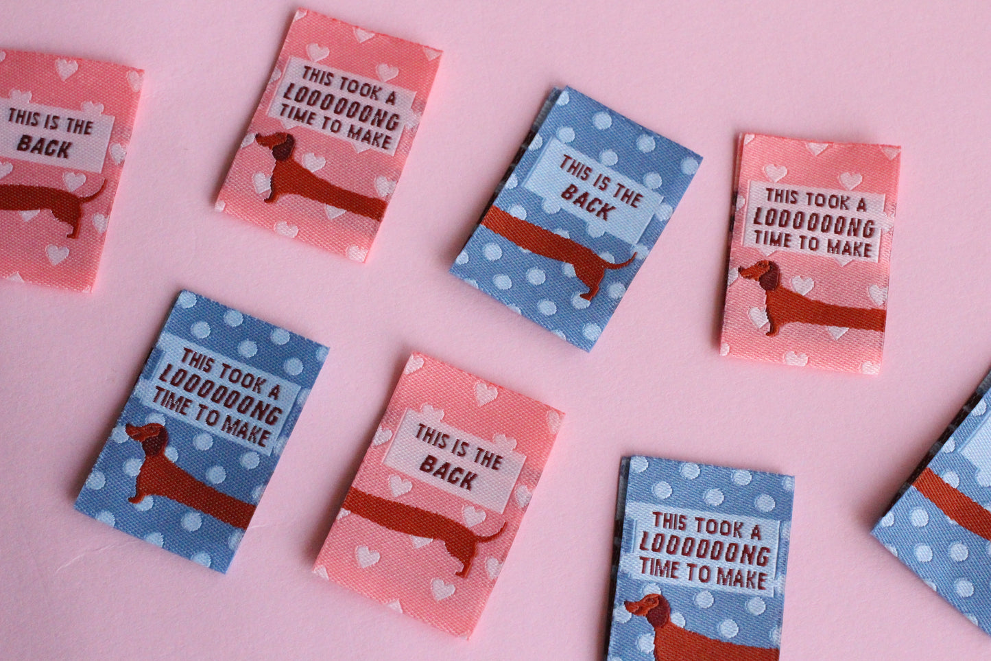 Pink and blue sausage dog sewing labels by The Cosy Club Handmade, double-sided fabric labels for sewing projects.