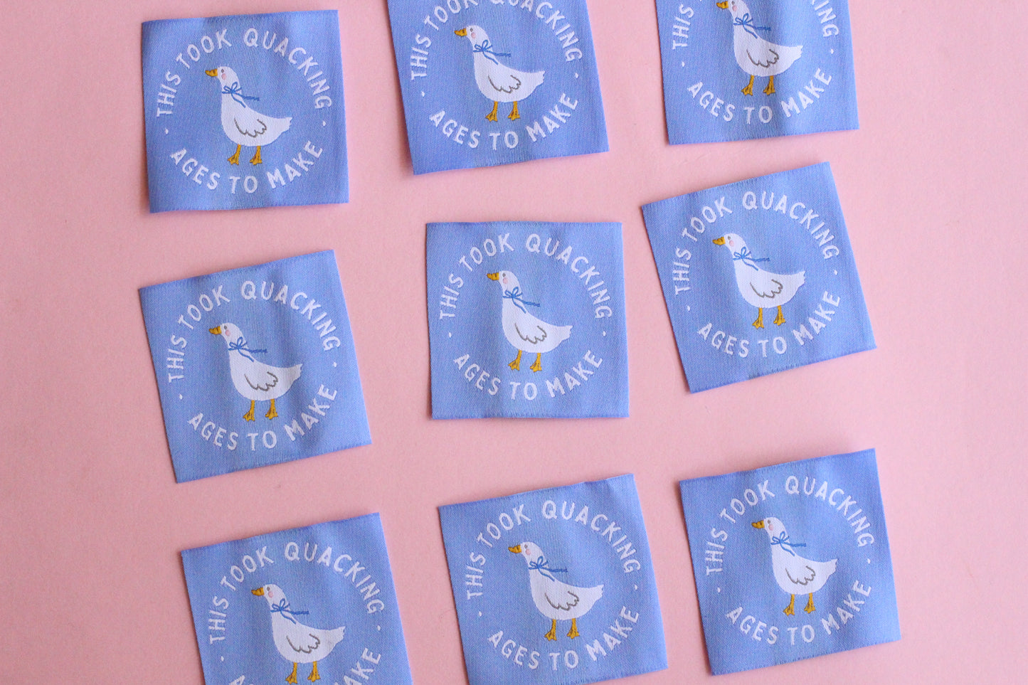 White goose sewing labels with "This Took Quacking Ages To Make" text from The Cosy Club Handmade, shown on a craft project.
