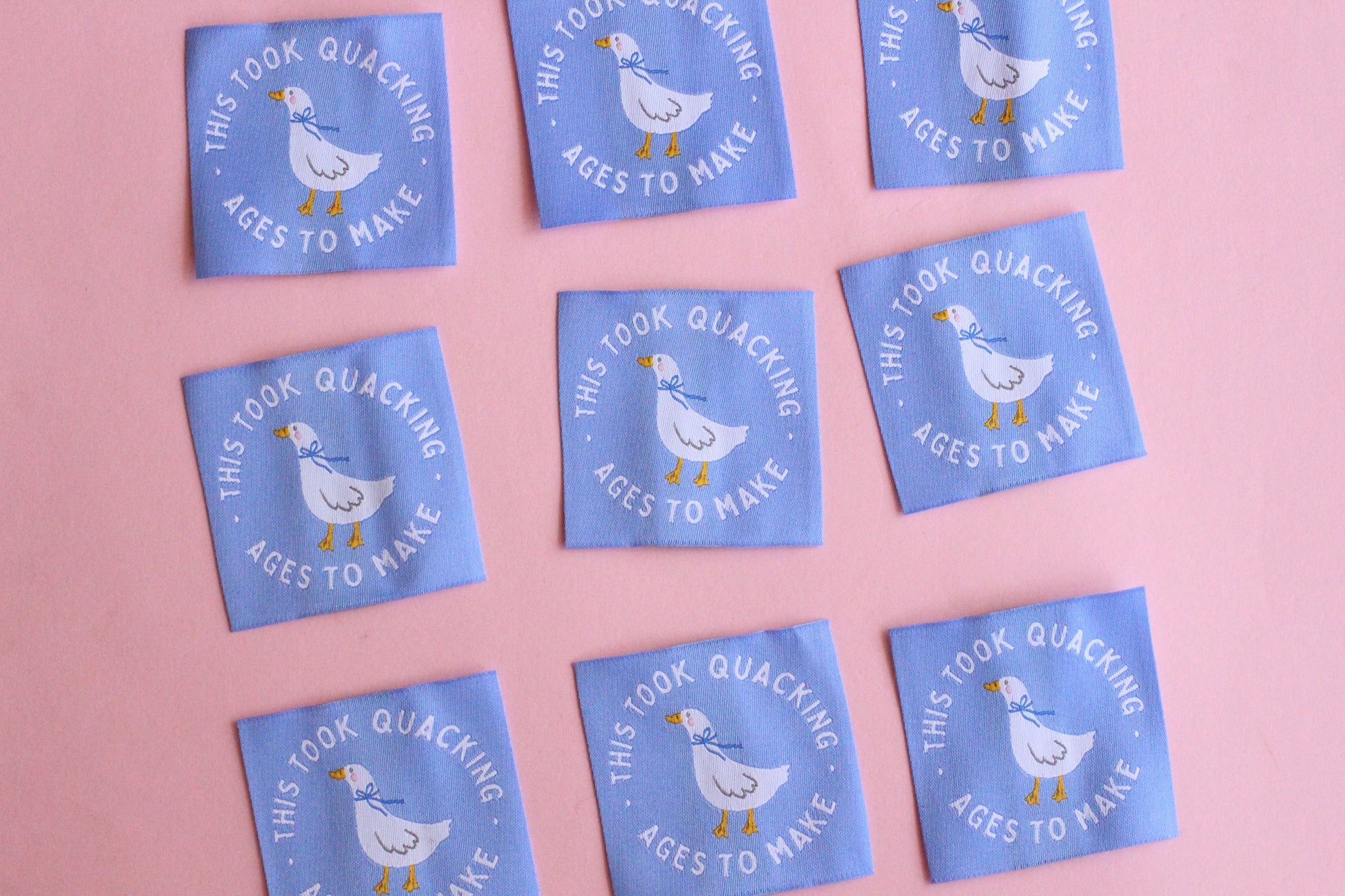White goose sewing labels with "This Took Quacking Ages To Make" text from The Cosy Club Handmade, shown on a craft project.