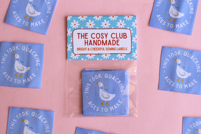 White goose sewing labels with "This Took Quacking Ages To Make" text, by The Cosy Club Handmade, featuring five labels on a white background.