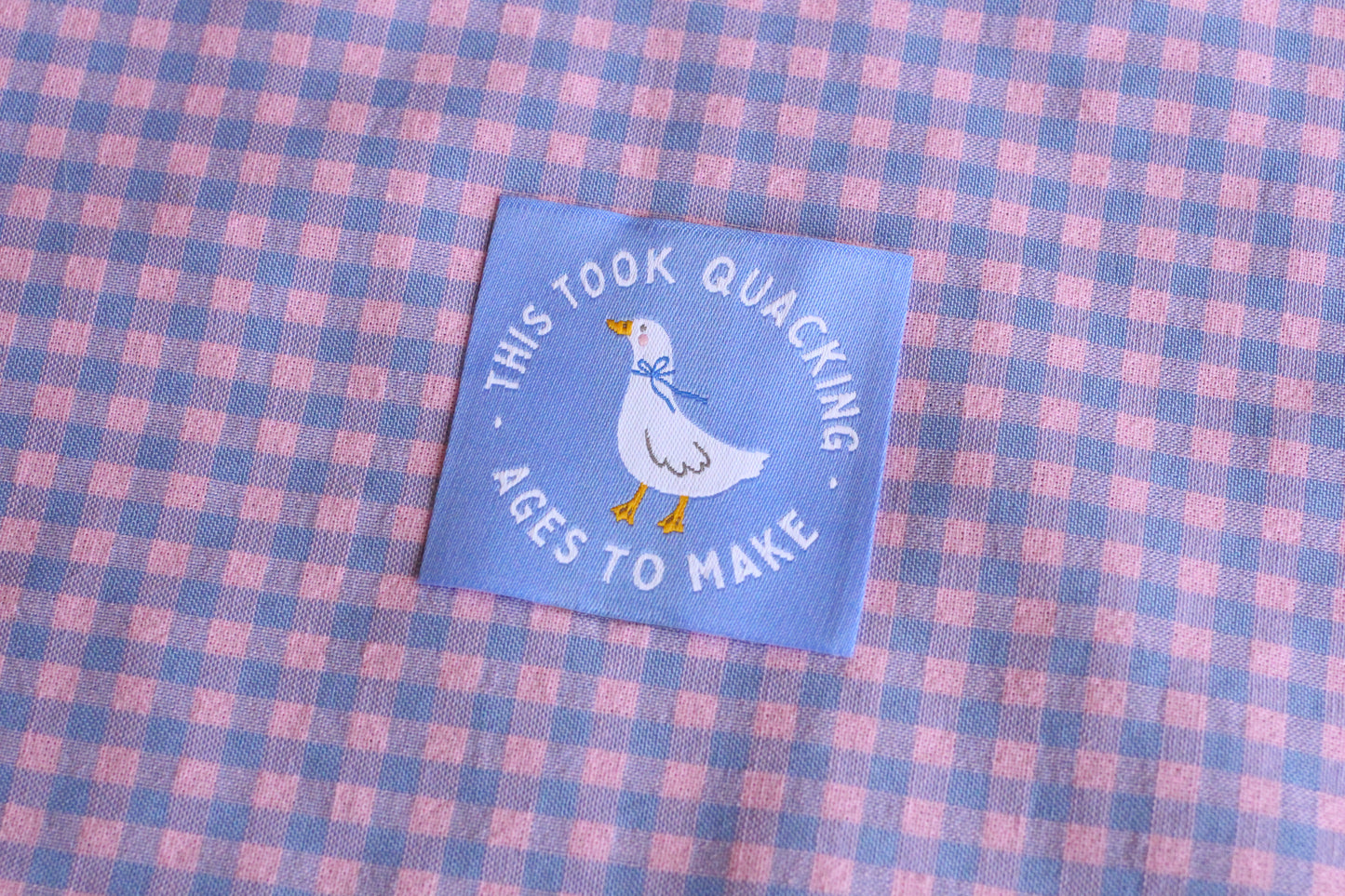 White goose sewing labels with "This Took Quacking Ages To Make" text from The Cosy Club Handmade, featuring five labels on a white background.