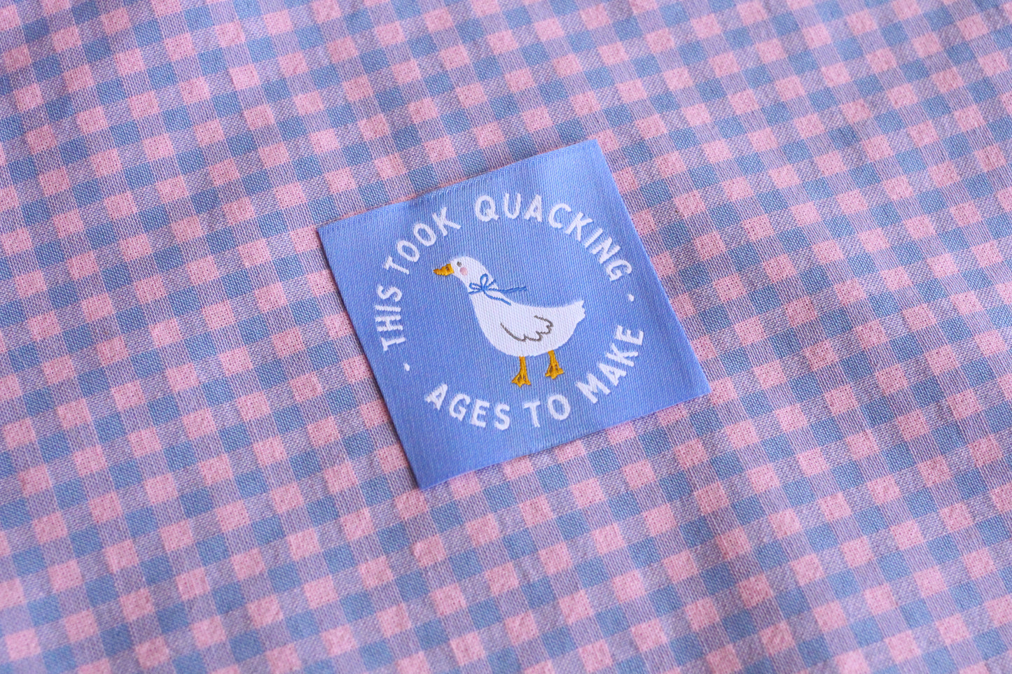 White goose sewing labels with "This Took Quacking Ages To Make" text by The Cosy Club Handmade, shown in close-up.