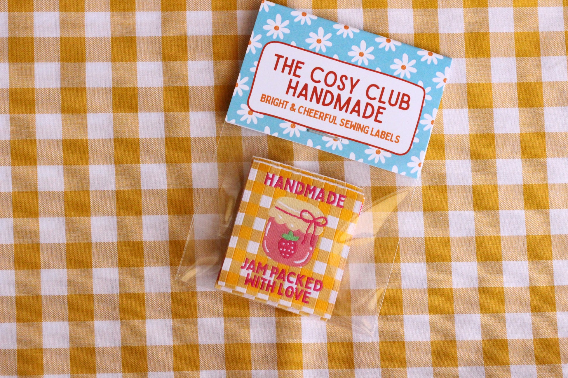 Handmade sewing labels with "Jam Packed With Love" by The Cosy Club Handmade, featuring colorful, fabric labels for homemade jams.