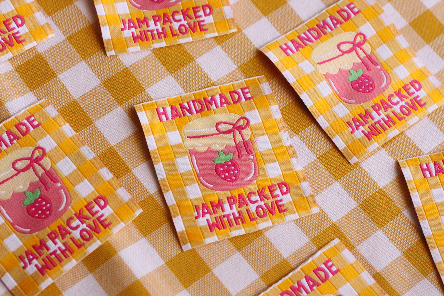 Handmade sewing labels with "Jam Packed With Love" by The Cosy Club Handmade, featuring colorful designs on fabric.